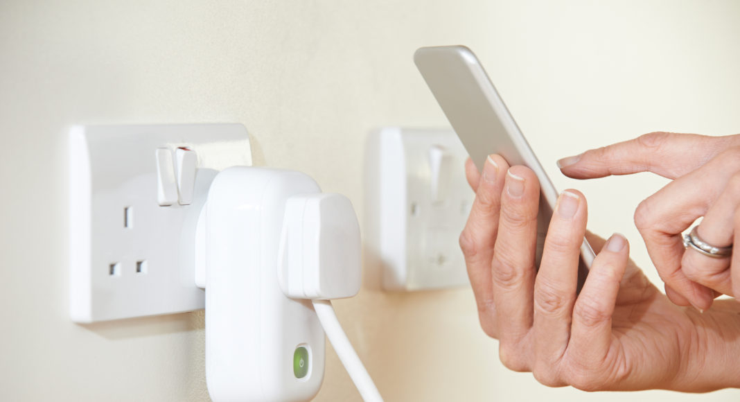 Woman Controlling Smart Plug Using App On Mobile Phone