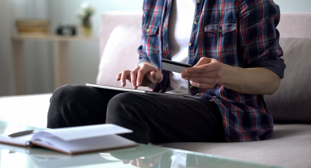 Man entering credit card data into tablet, paying for airline ticket, booking ciberamenazas